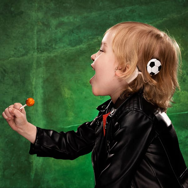 Child wearing Football hearing aid accessory from DeafMetal