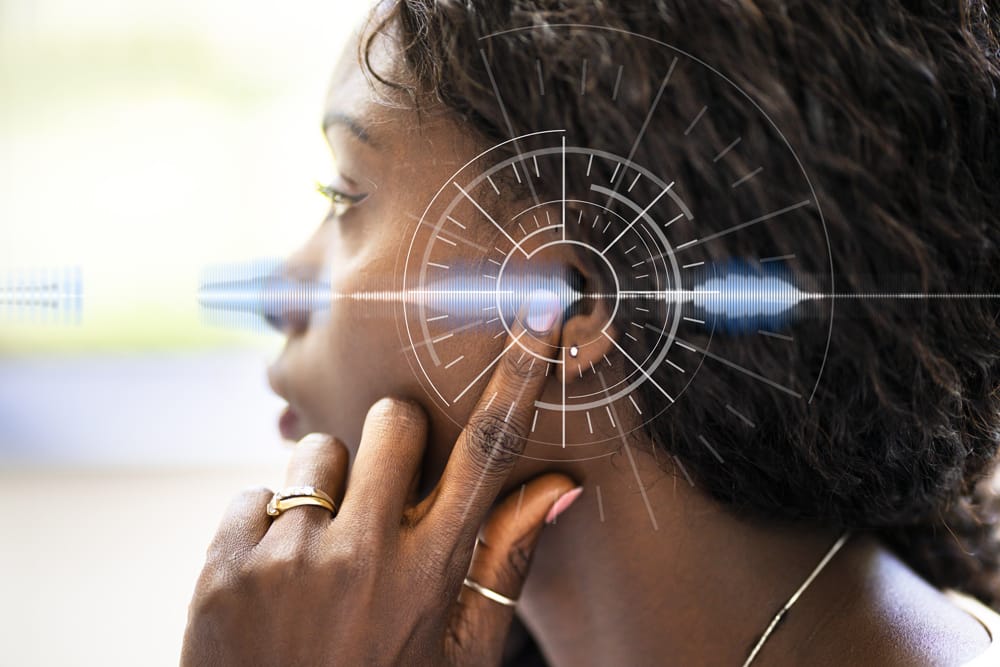 Close-up of the profile of a woman pointing toward her ear; Circular shapes with lines going across encircling the ear
