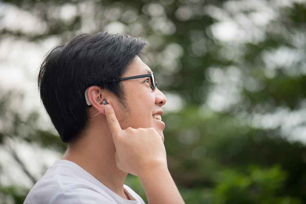 Asian man with hearing aid behind the ear outdoors