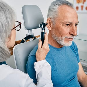 Senior man having his ear examined by an audiologist.