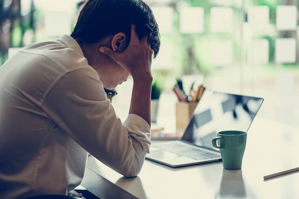 Young man in office in front of laptop looking frustrated and confused