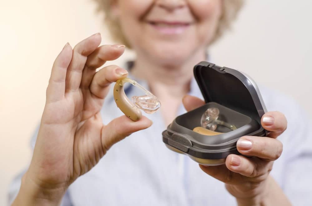Senior woman holding a pair of hearing aids