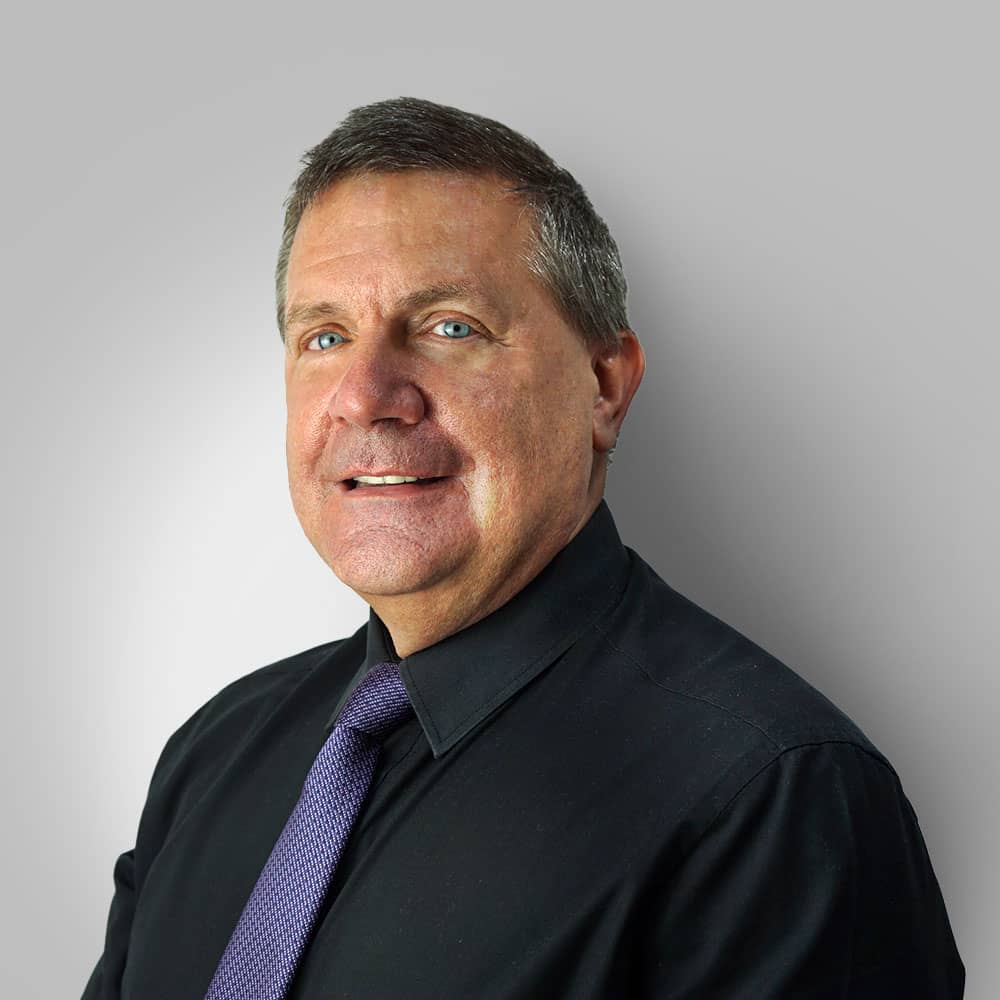Photograph of male audiologist (Roger) wearing black office shirt with purple tie