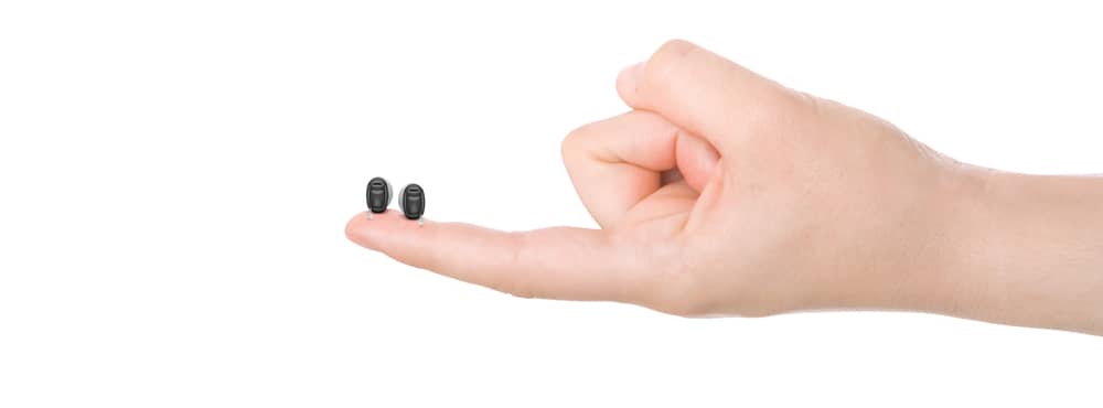 Two miniature hearing aids being held on one finger
