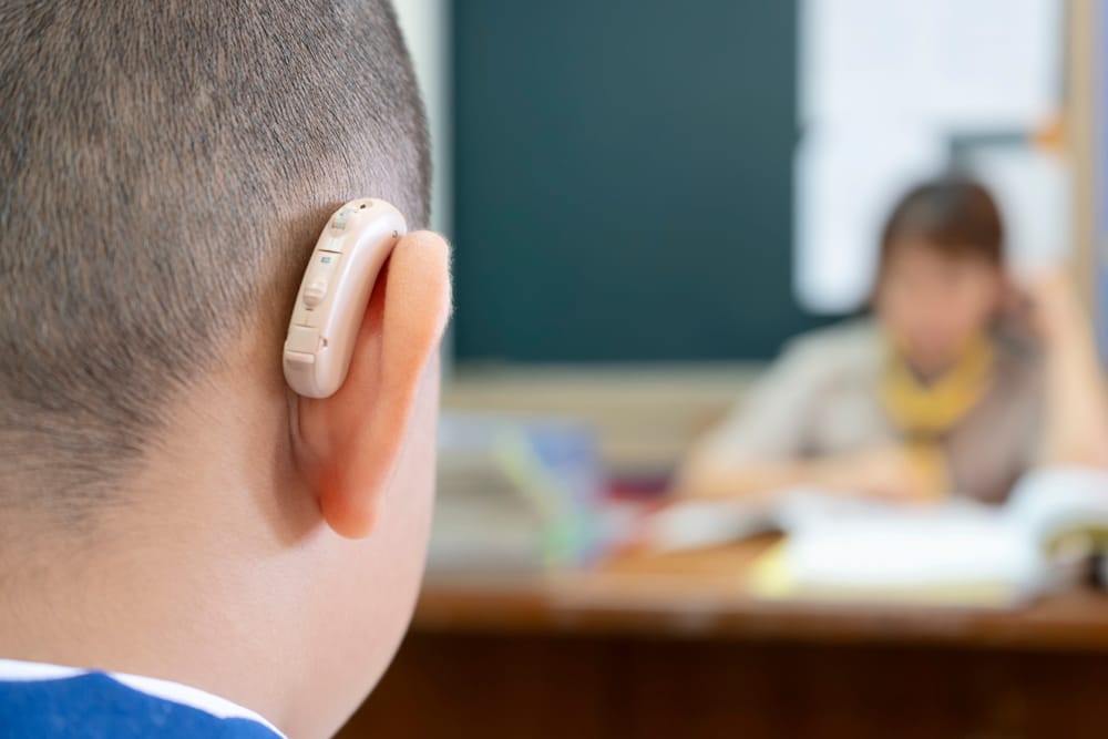 Young student wearing hearing aid in class