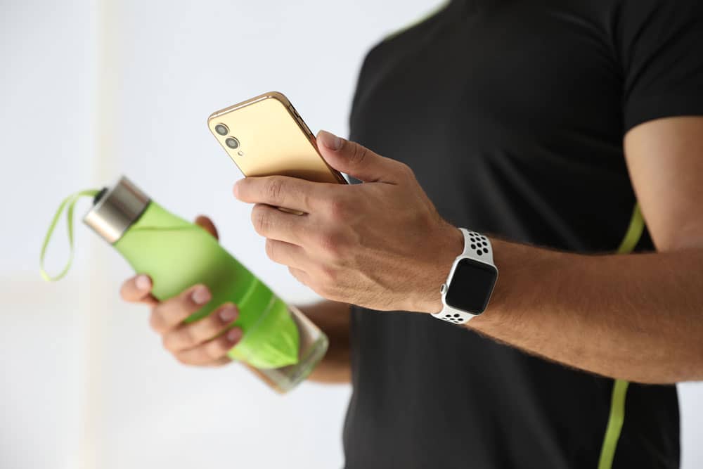 Male hands holding a phone and a water bottle