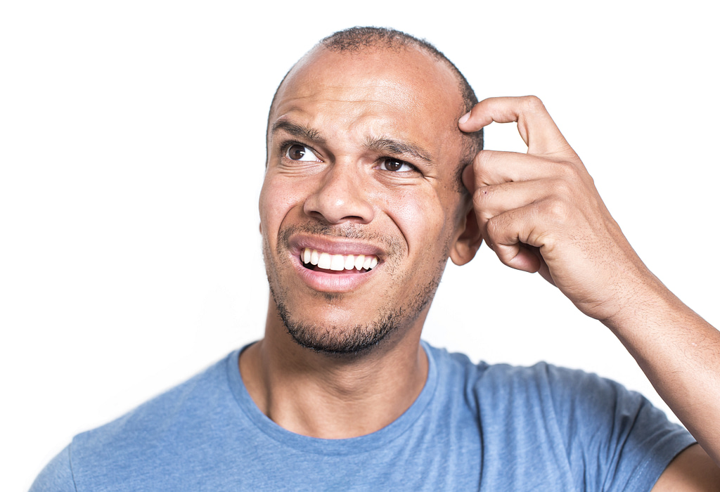 Portrait of a mixed race man scratching his head in confusion on white background