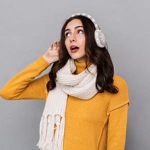 Brown haired woman wearing ear mufflers struggling to hear