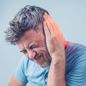 male having ear pain touching his painful head isolated on gray