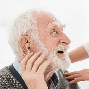 Cheerful elderly man with hearing aid in one ear