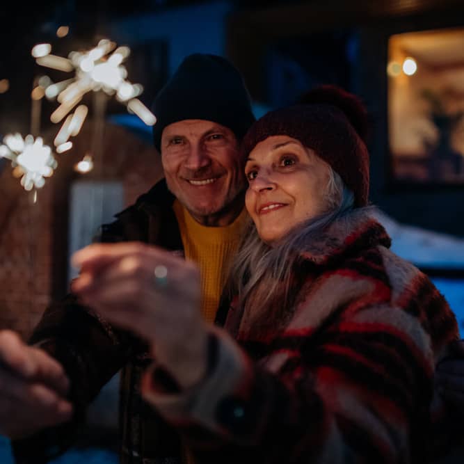 A senior couple enjoying sparklers outdoors.